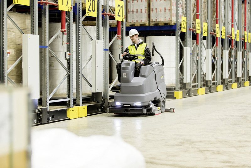 Karcher B 150 R ride-on scrubber cleaning a warehouse aisle
