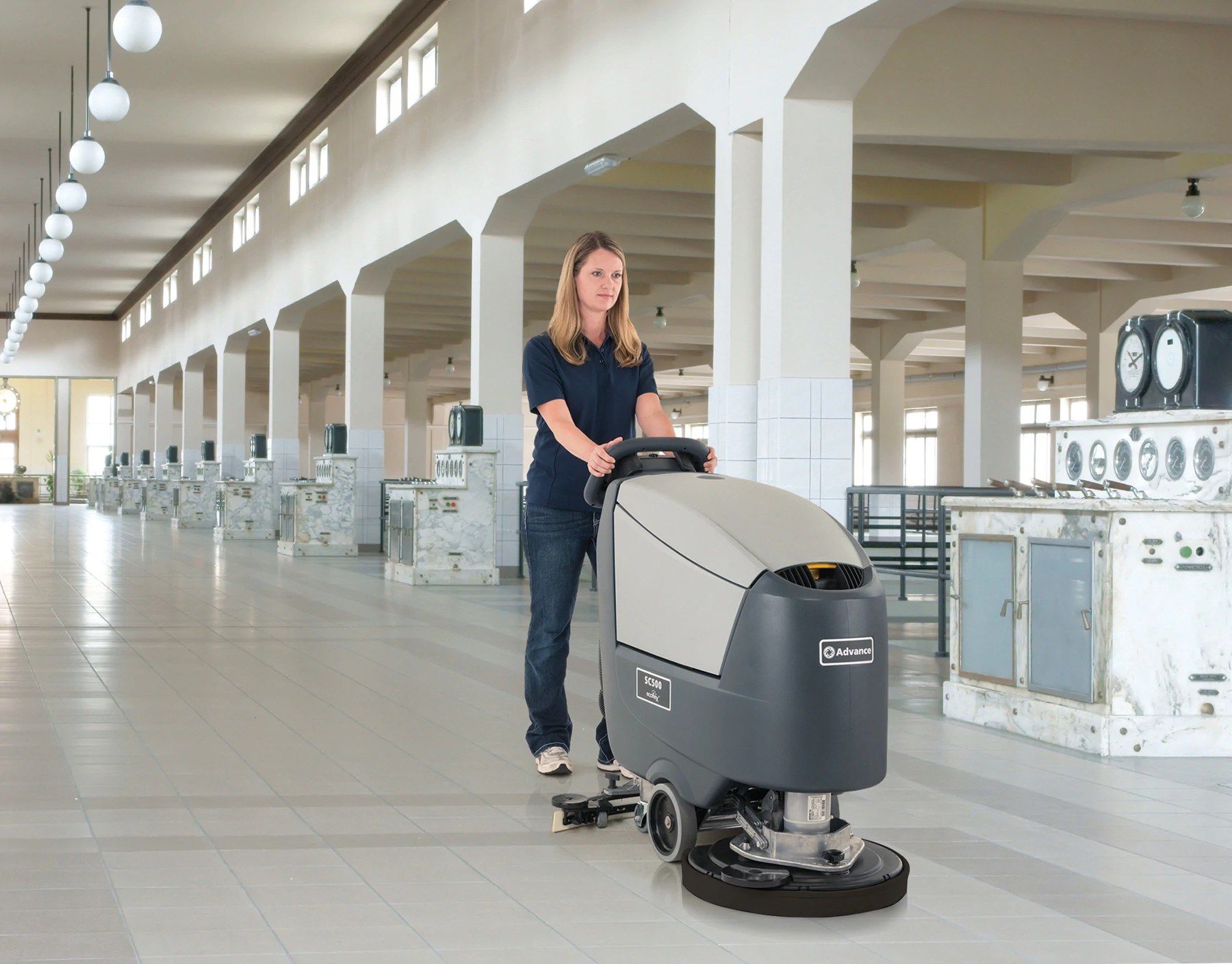 Operator scrubbing a long industrial hall with an Advance SC500 disc scrubber