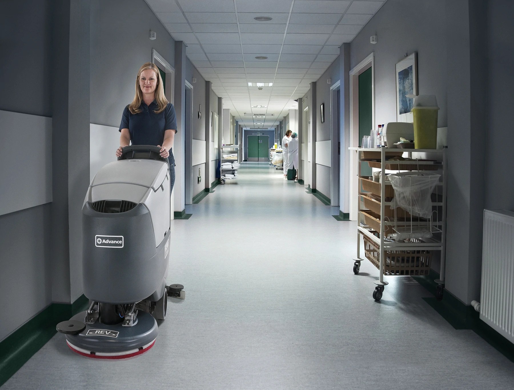 Operator scrubbing a hospital room floor with an Advance SC500 REV scrubber