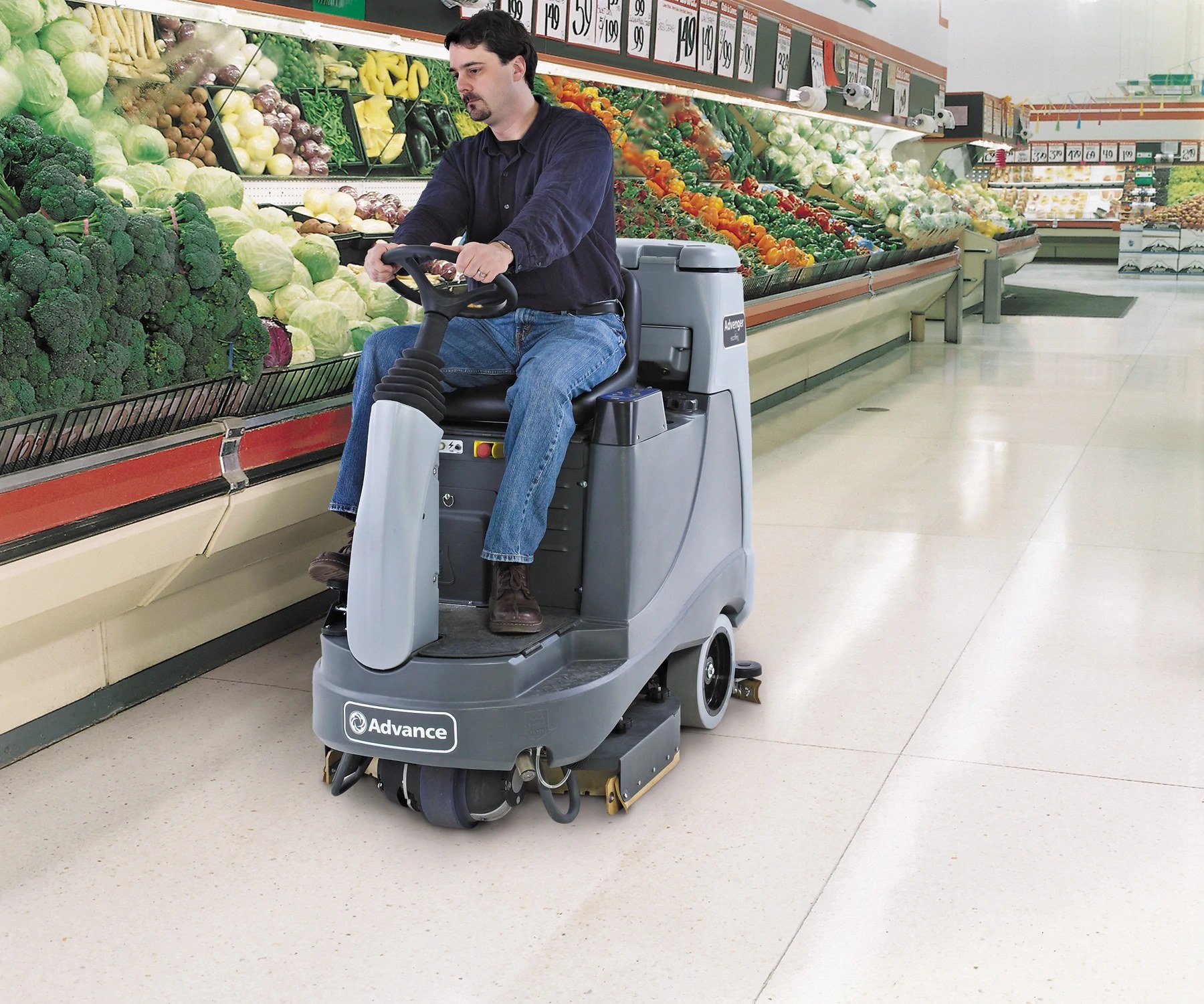 Operator riding an Advance Advenger disc scrubber past the produce department in a grocery store