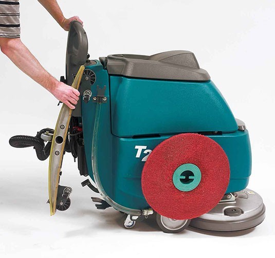 Operator attaching a red pad to the Tennant T2 pad driver with the machine tilted back