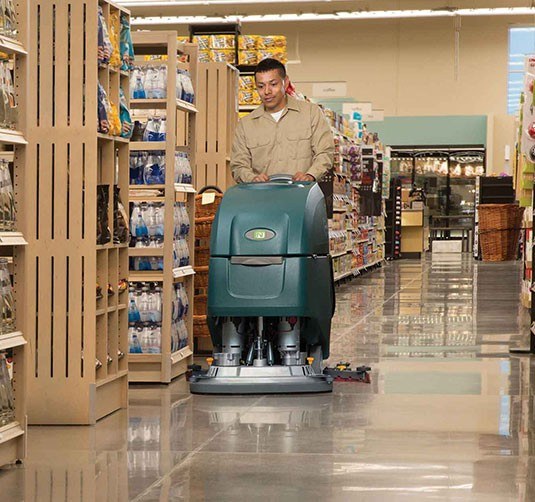 Operator running the Nobles Speed Scrub 500 disk walk-behind scrubber down a grocery store aisle