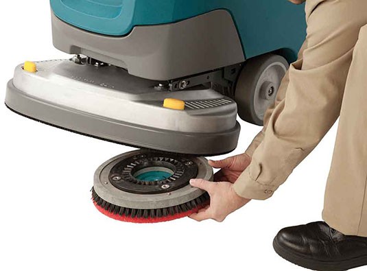 Operator attaching a pad driver to the Insta-Click magnetic scrub head on a Tennant T300