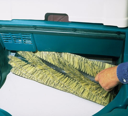 Operator removing the quick-release main broom from a Tennant 3640 sweeper without tools