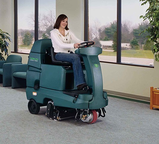 Operator driving a Nobles Strive Rider across office carpet