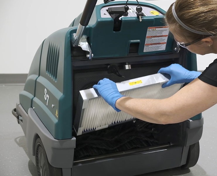 Operator removing the panel dust filter from the front of the Tennant S7 sweeper