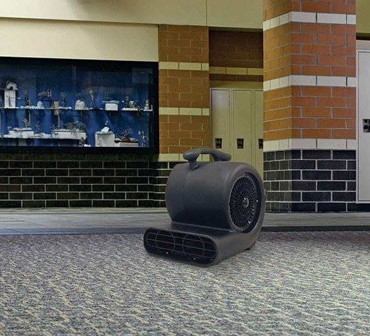 Tennant blower drying carpet in a building hallway