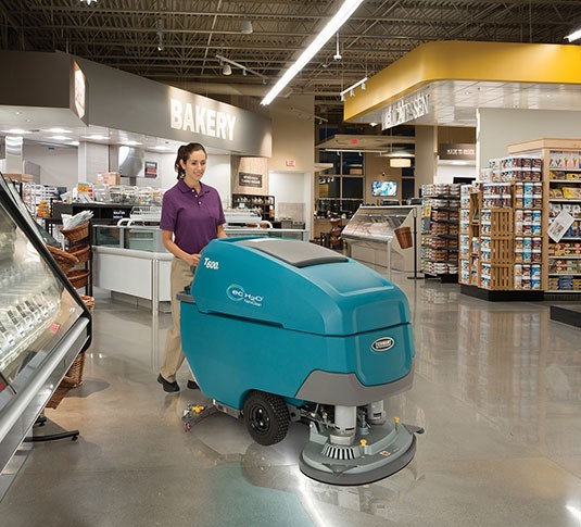 Operator cleaning a grocery store floor with a Tennant T600 disk scrubber equipped with ec-H2O NanoClean