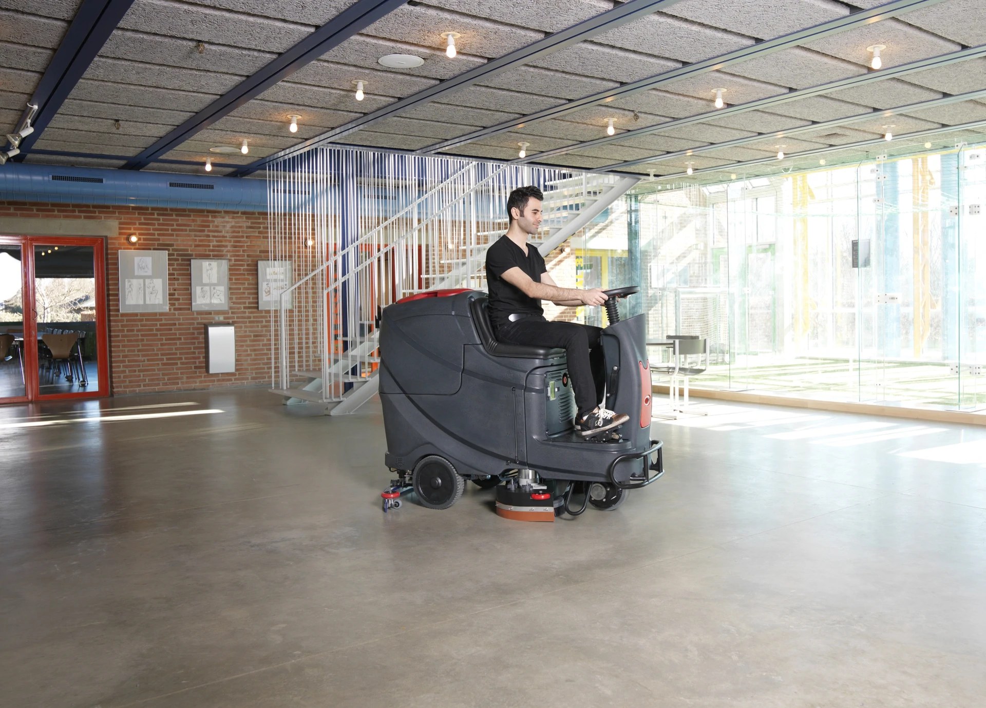 Operator riding a Viper AS710R scrubber across a large open lobby floor