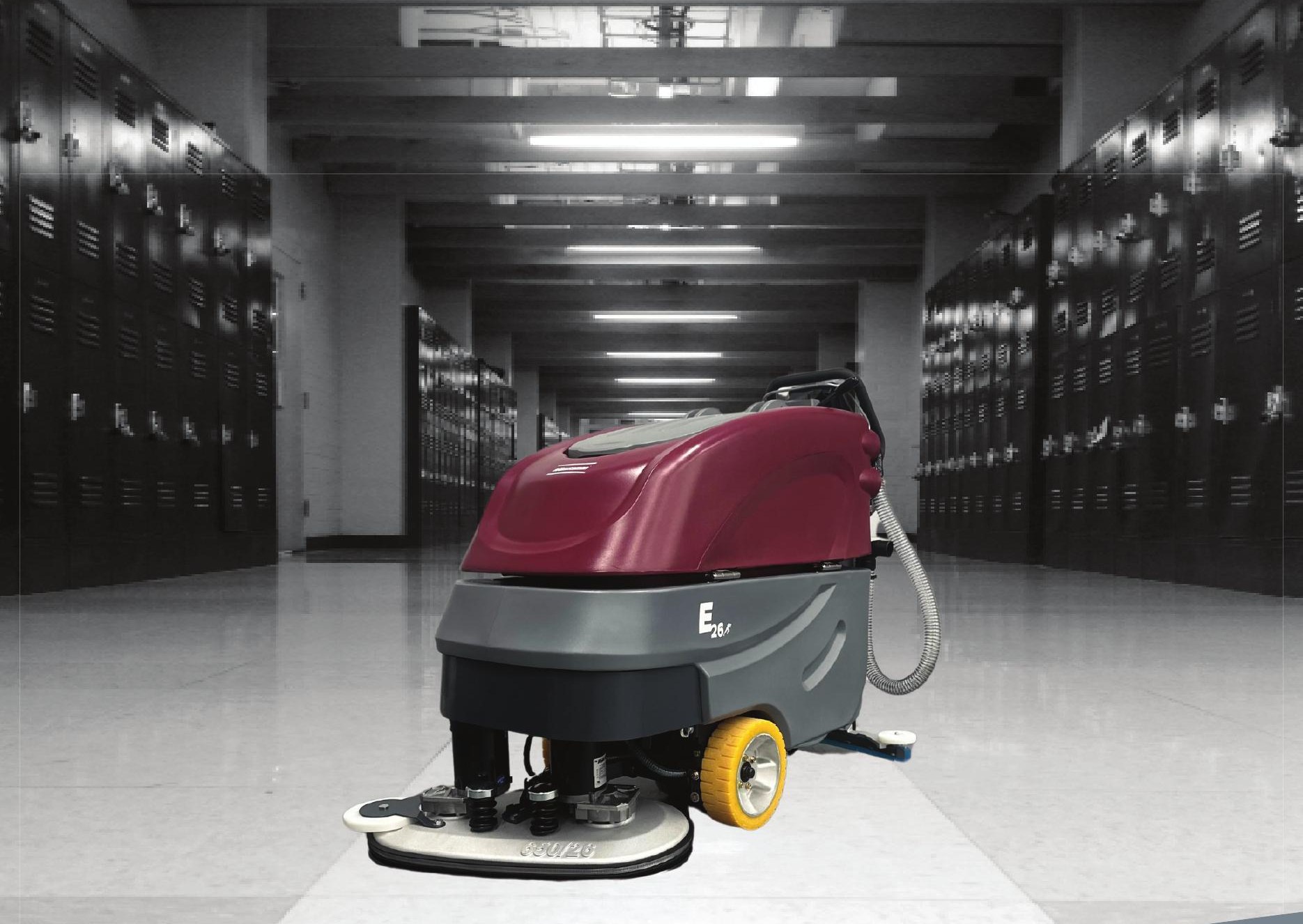 Minuteman E26 walk-behind disc floor scrubber in a school hallway lined with lockers