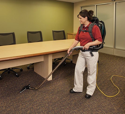 Operator vacuuming a conference room carpet with the Tennant V-BP-6 backpack vacuum
