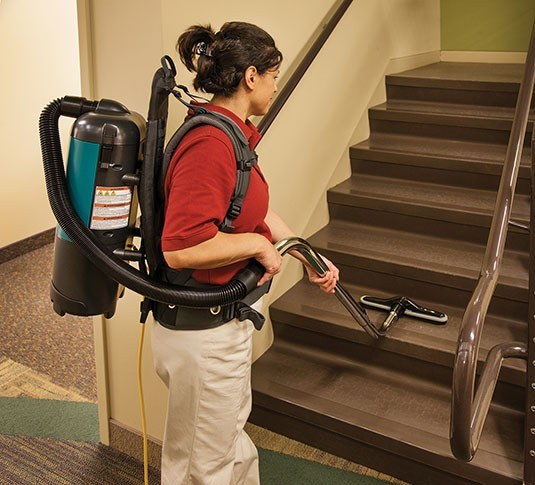 Operator vacuuming carpeted stairs with the Tennant V-BP-6 backpack vacuum