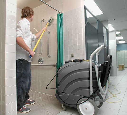 Operator cleaning a shower stall wall with the Tennant ASC-15