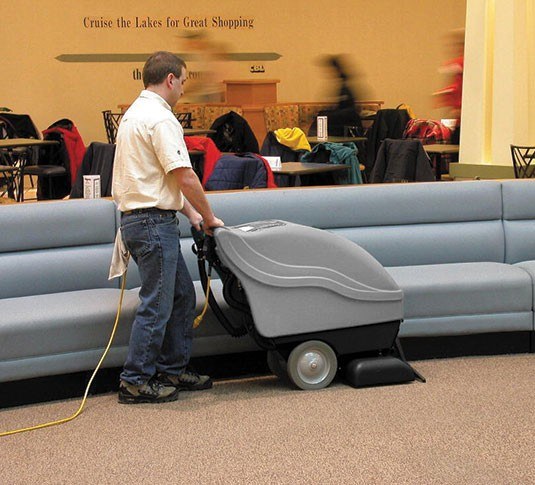 Operator cleaning carpet beside booth seating with the Tennant EX-SC-1020