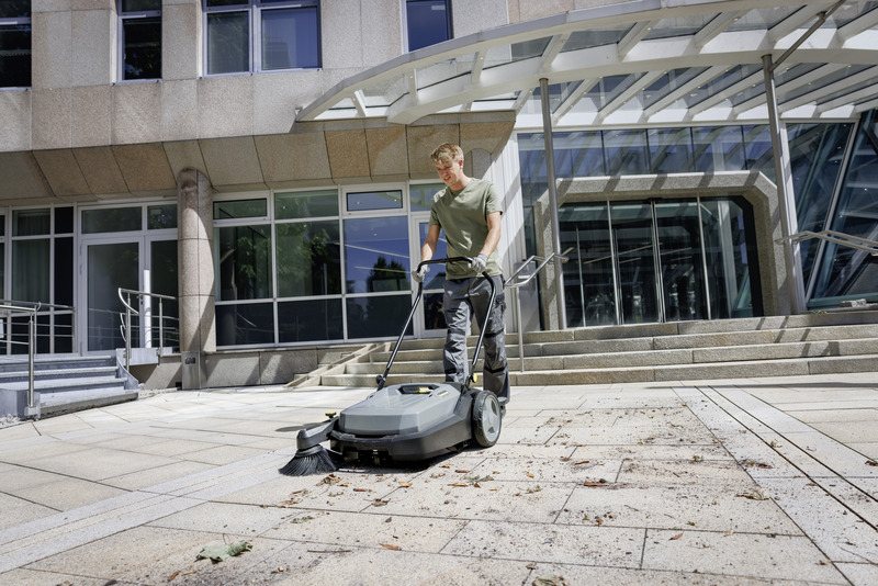 Karcher KM 70/20 C manual sweeper cleaning an outdoor building entrance