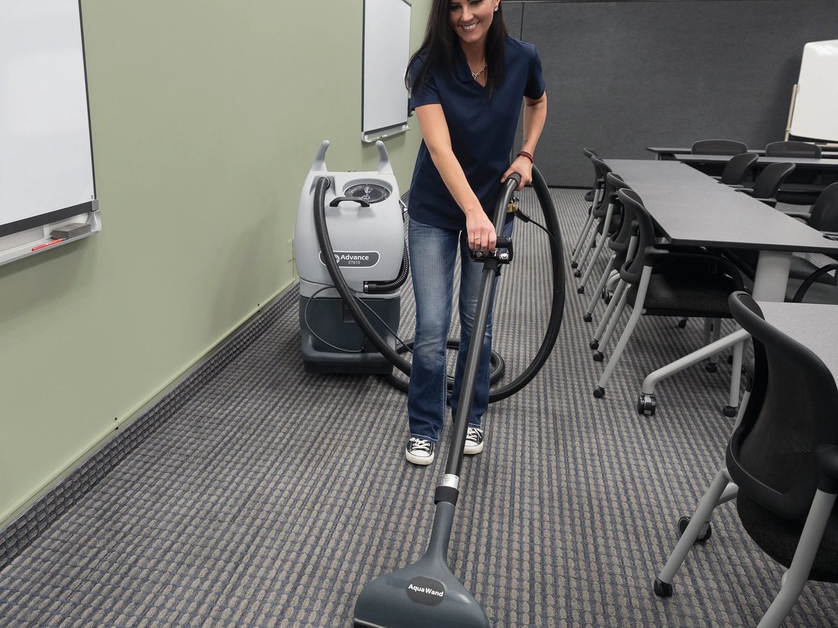Operator extracting classroom carpet with an Advance ET610 and floor wand