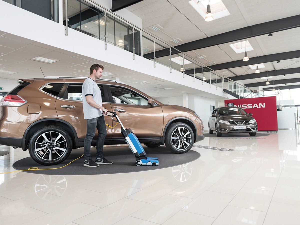 Worker scrubbing a car showroom floor with a Clarke MA10 12E
