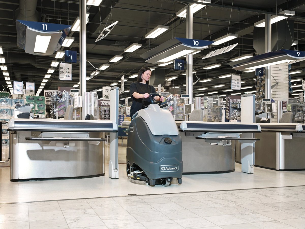 Operator scrubbing a supermarket checkout area with an Advance SC1500