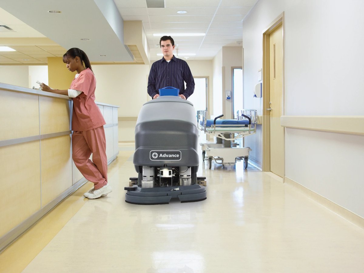 Operator scrubbing a hospital corridor with an Advance SC800 walk-behind scrubber