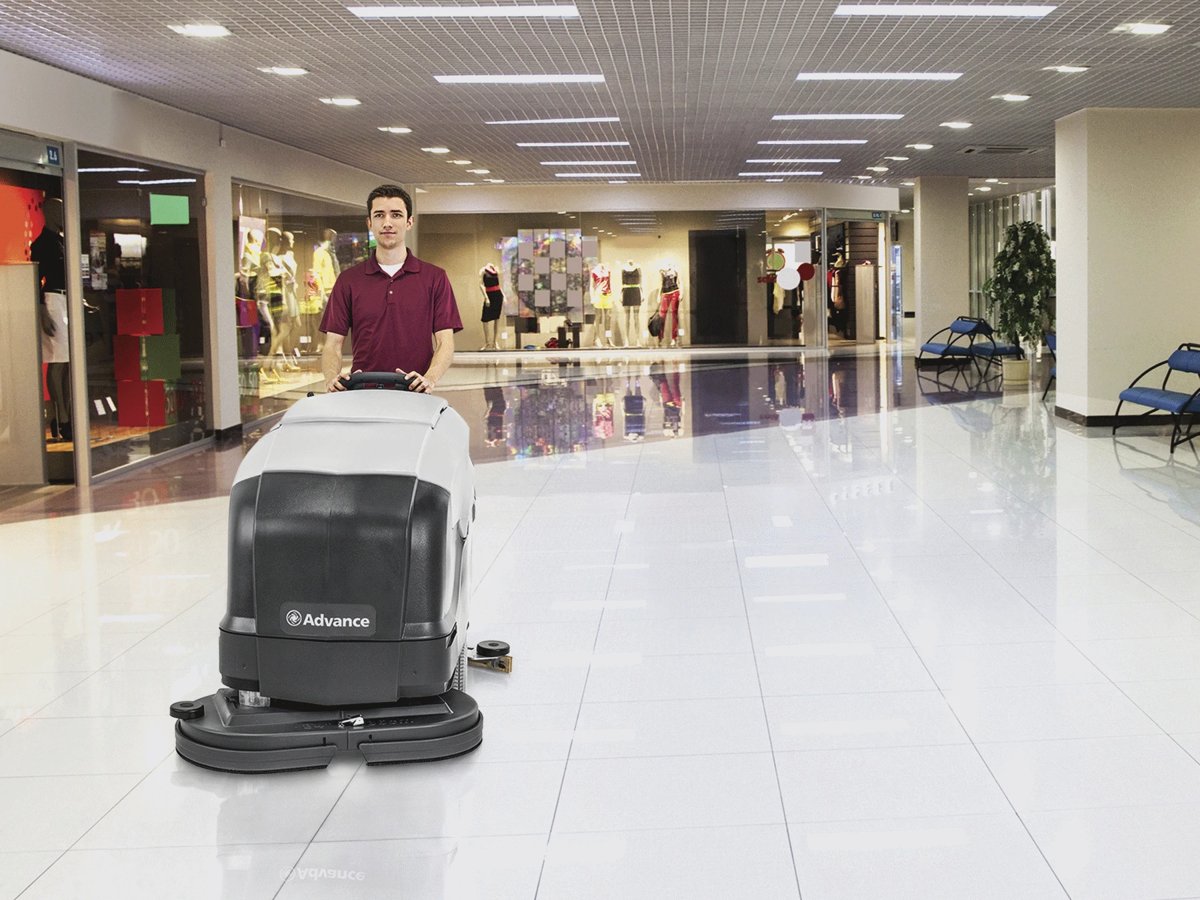 Operator scrubbing a shopping mall floor with an Advance SC901 walk-behind scrubber