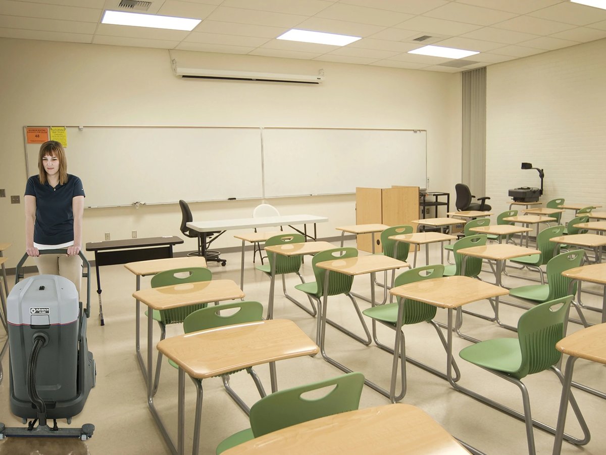 Custodian rolling an Advance VL500 75 wet/dry vacuum through a classroom
