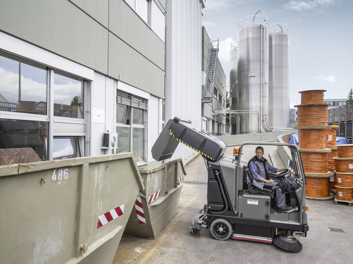 Kärcher B 300 R I emptying its debris container into a dumpster with the hydraulic high dump