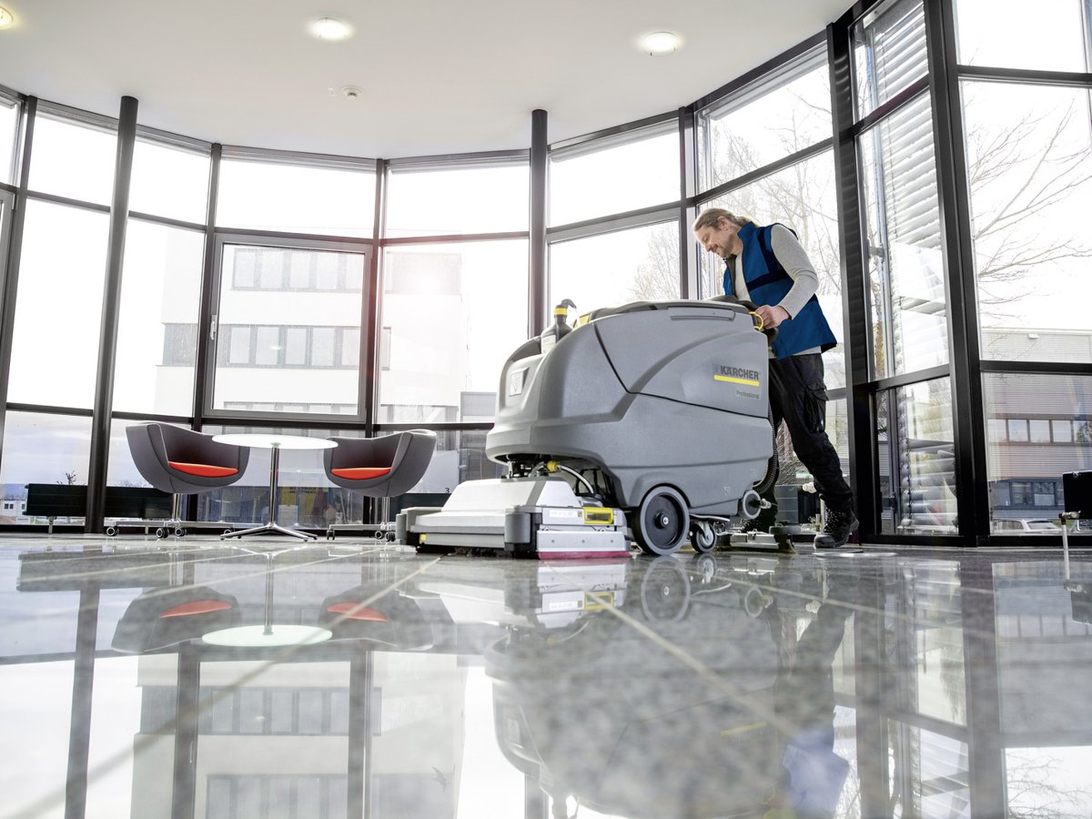 Operator scrubbing a polished lobby floor with a Kärcher B 80 W Bp