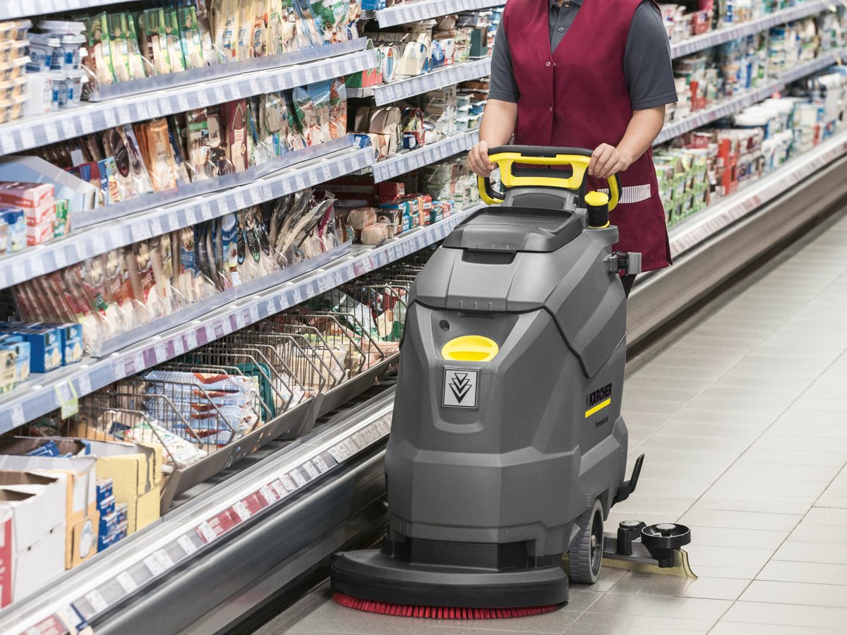 Worker scrubbing a grocery store aisle with a Kärcher BD 50/50 C Bp Classic