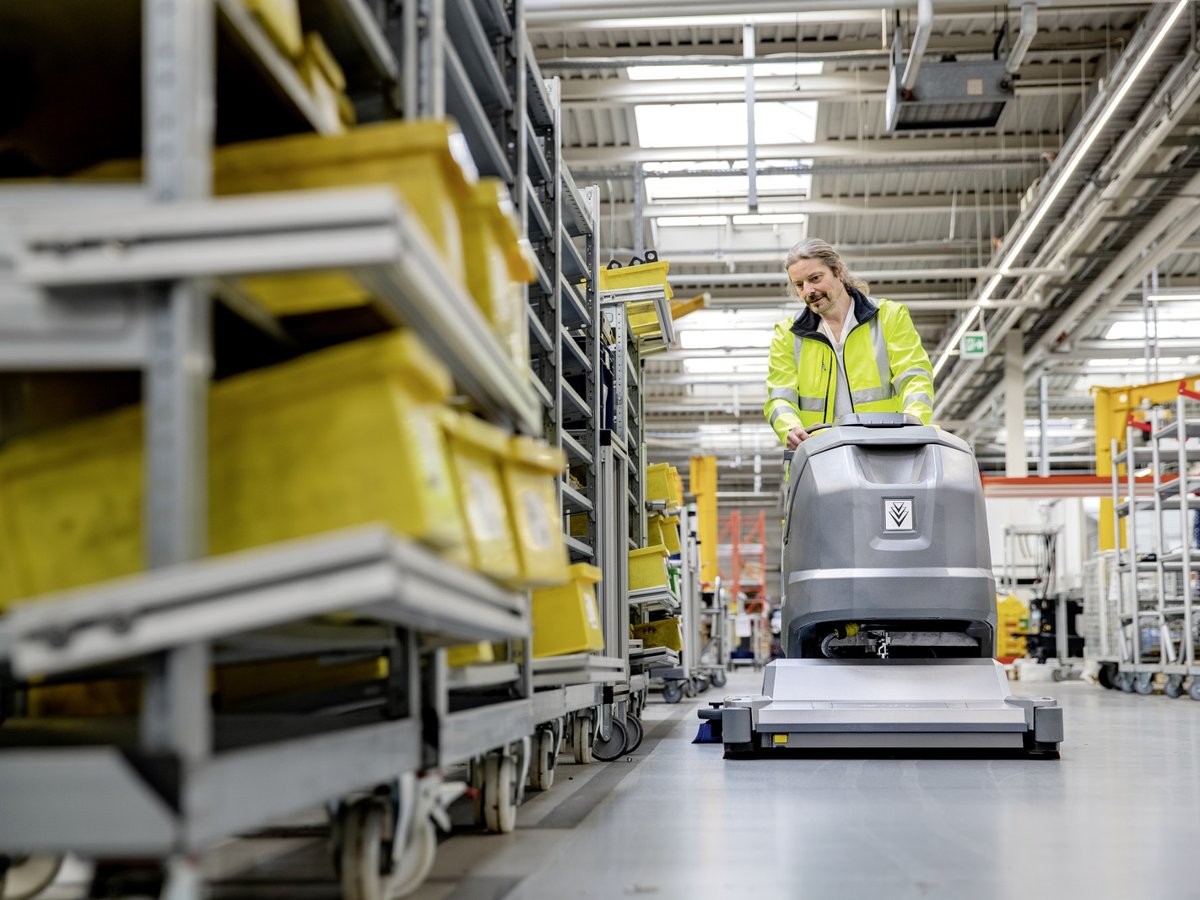 Worker in hi-vis scrubbing a warehouse aisle with a Kärcher BR 85/100 W Bp Classic
