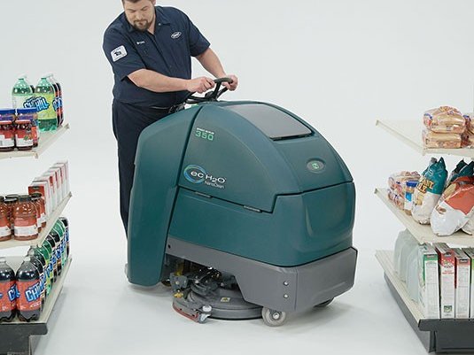 Operator riding a Nobles Speed Scrub 350 between retail store shelves