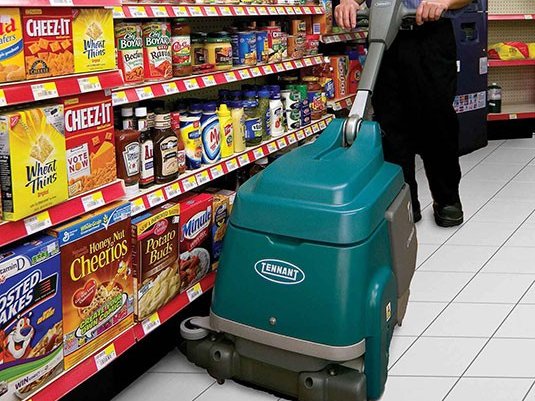 Operator using a Tennant T1B micro scrubber in a convenience store aisle