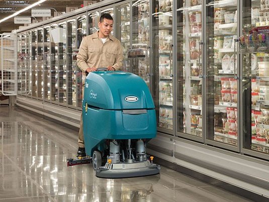 Operator scrubbing a grocery store frozen-food aisle with a Tennant T500e