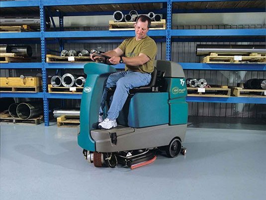 Operator scrubbing a warehouse floor with a Tennant T7 with ec-H2O NanoClean