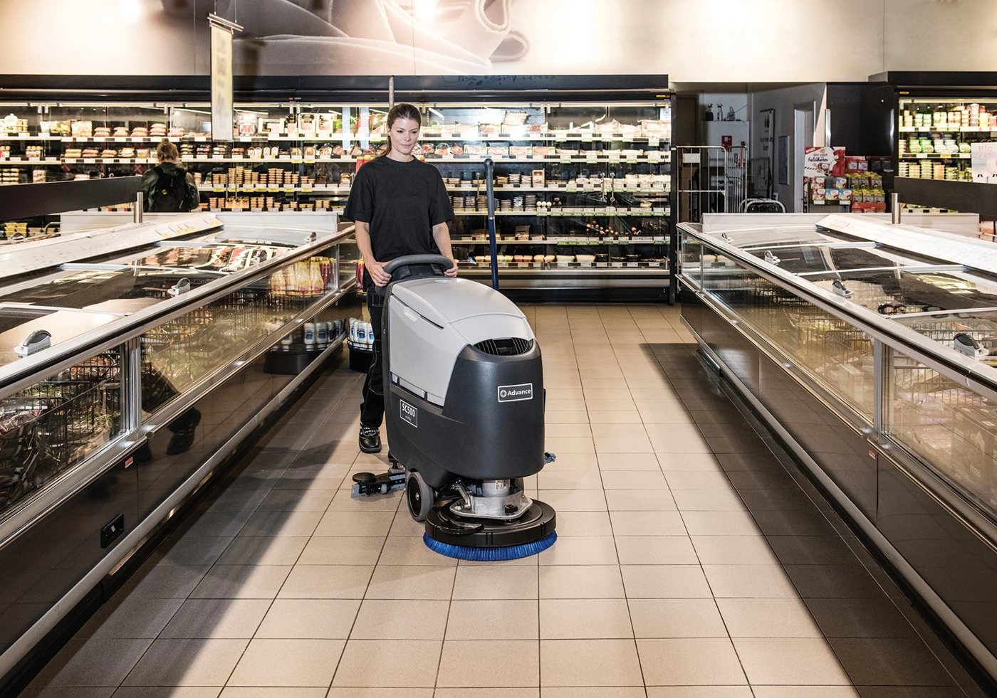 Advance SC500 walk-behind scrubber cleaning a supermarket aisle